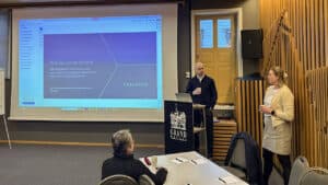 Konferanserom med deltakere og en person som presenterer noe på et stort lerret