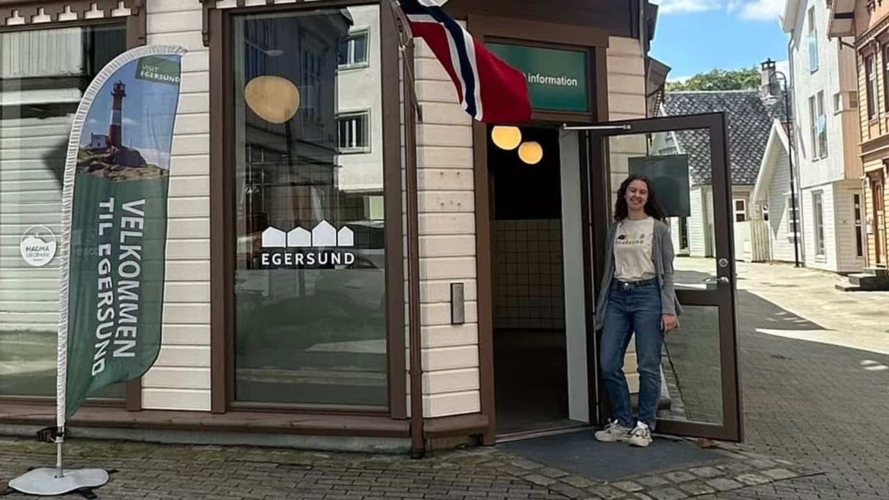 En turistvert som står utenfor turistinformasjonen og ønsker velkommen